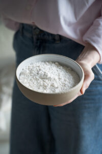 glutenfreies Mehl in einer beigen Keramikschüssel, gehalten von einer Hand