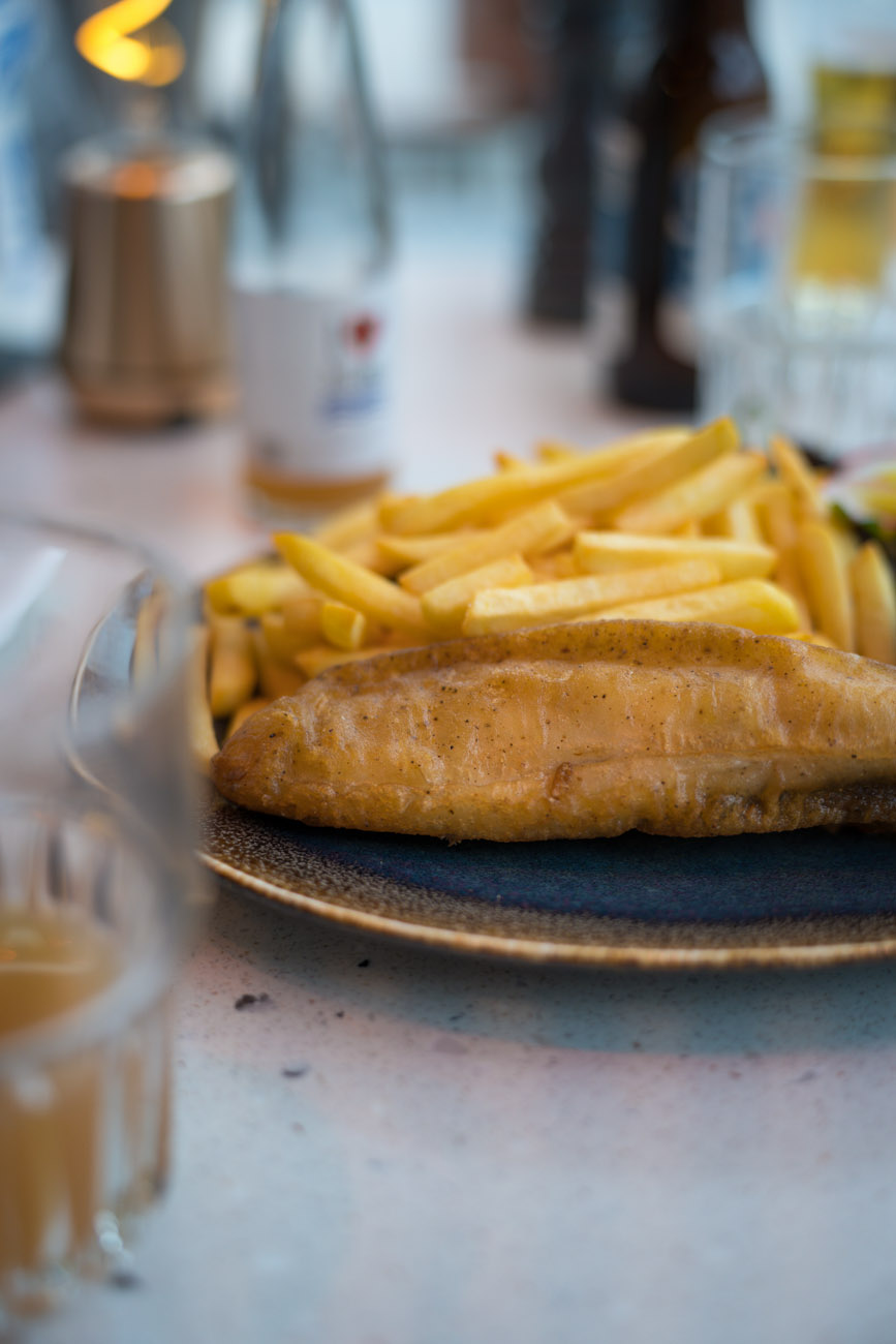 Ein Teller mit Pommes und frittiertem Backfisch.