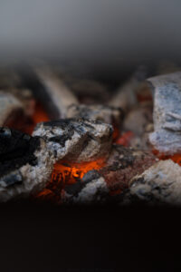 Man sieht Grillkohle, die leicht voller Asche und unten glutrot/Orange ist,
