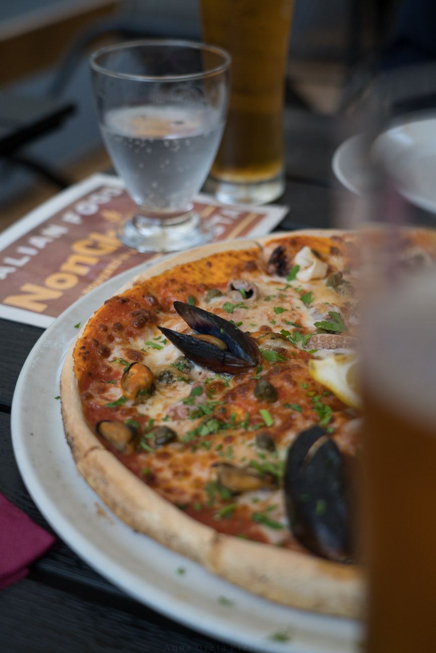 glutenfreie Pizza mit Meeresfrüchten, im Hintergrund sieht man ein Glas Wasser