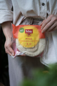 Eine orange/gelbe Verpackung mit Pitas, von zwei Händen gehalten