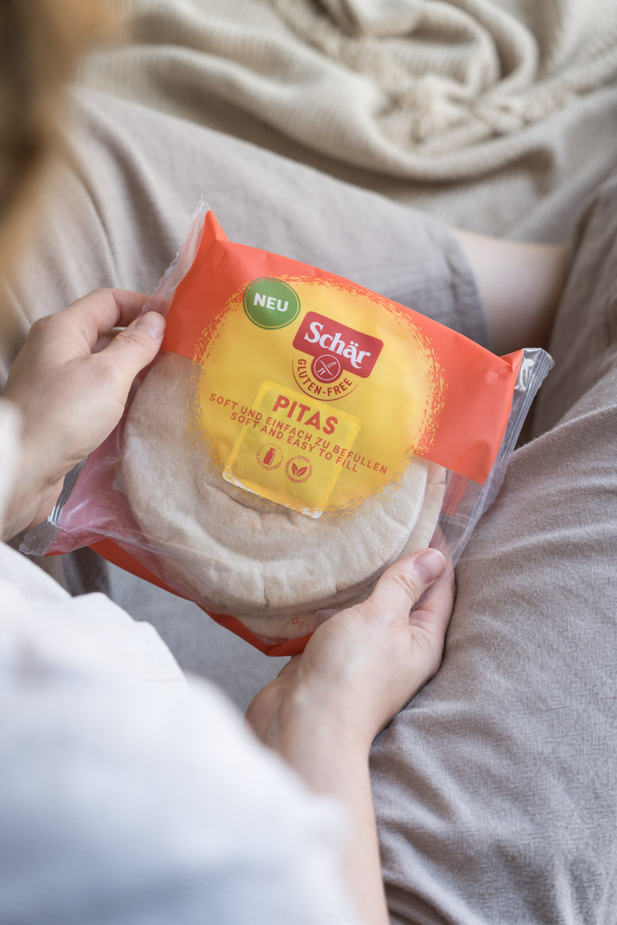 Eine Verpackung mit glutenfreien Pitas, gehaöten von zwei Händen, von oben über die Schulter fotografiert