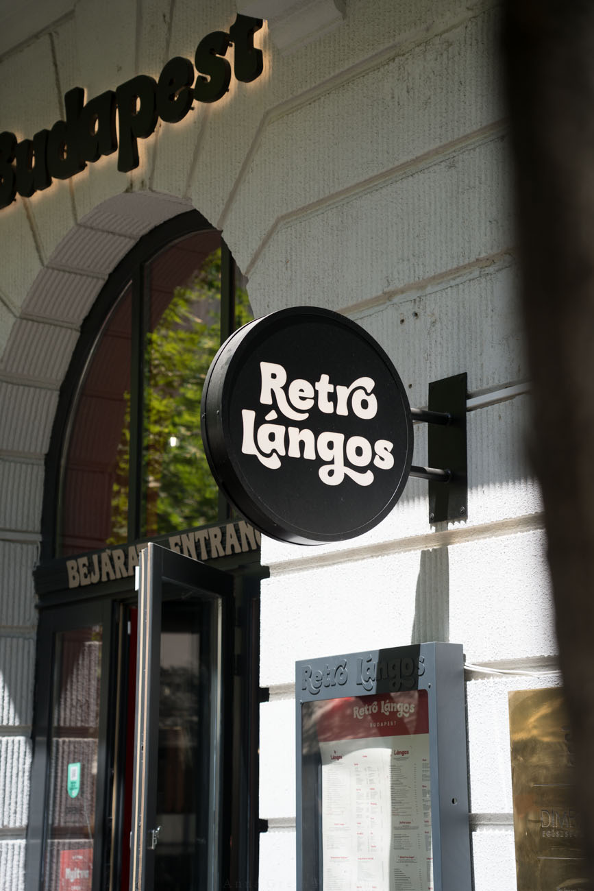 Rundes Schild an Hausfassade mit der Aufschrift "Retro Langos" in Budapest