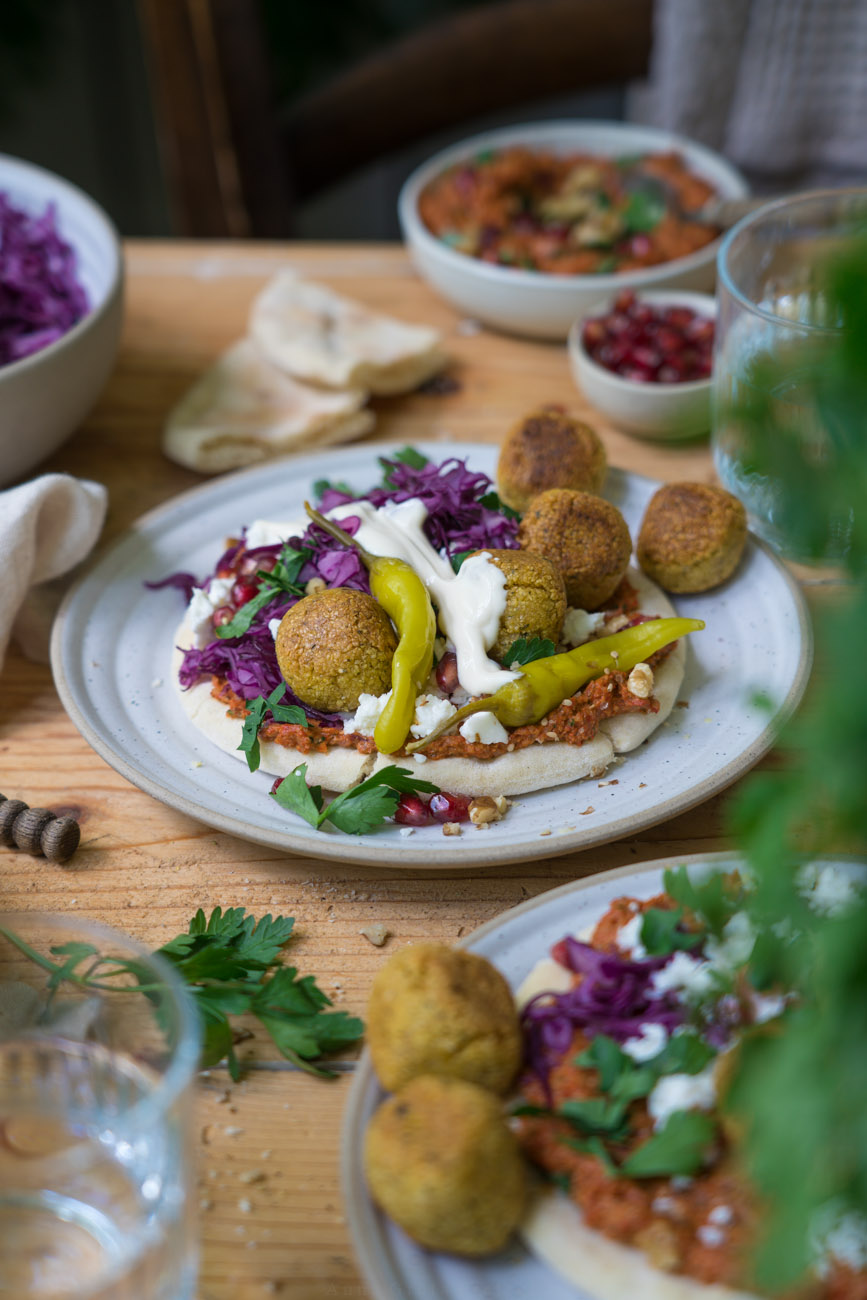 Eine bunt belegte Pita mit Falafeln, Muhammara-Dip, Peperoni, Feta