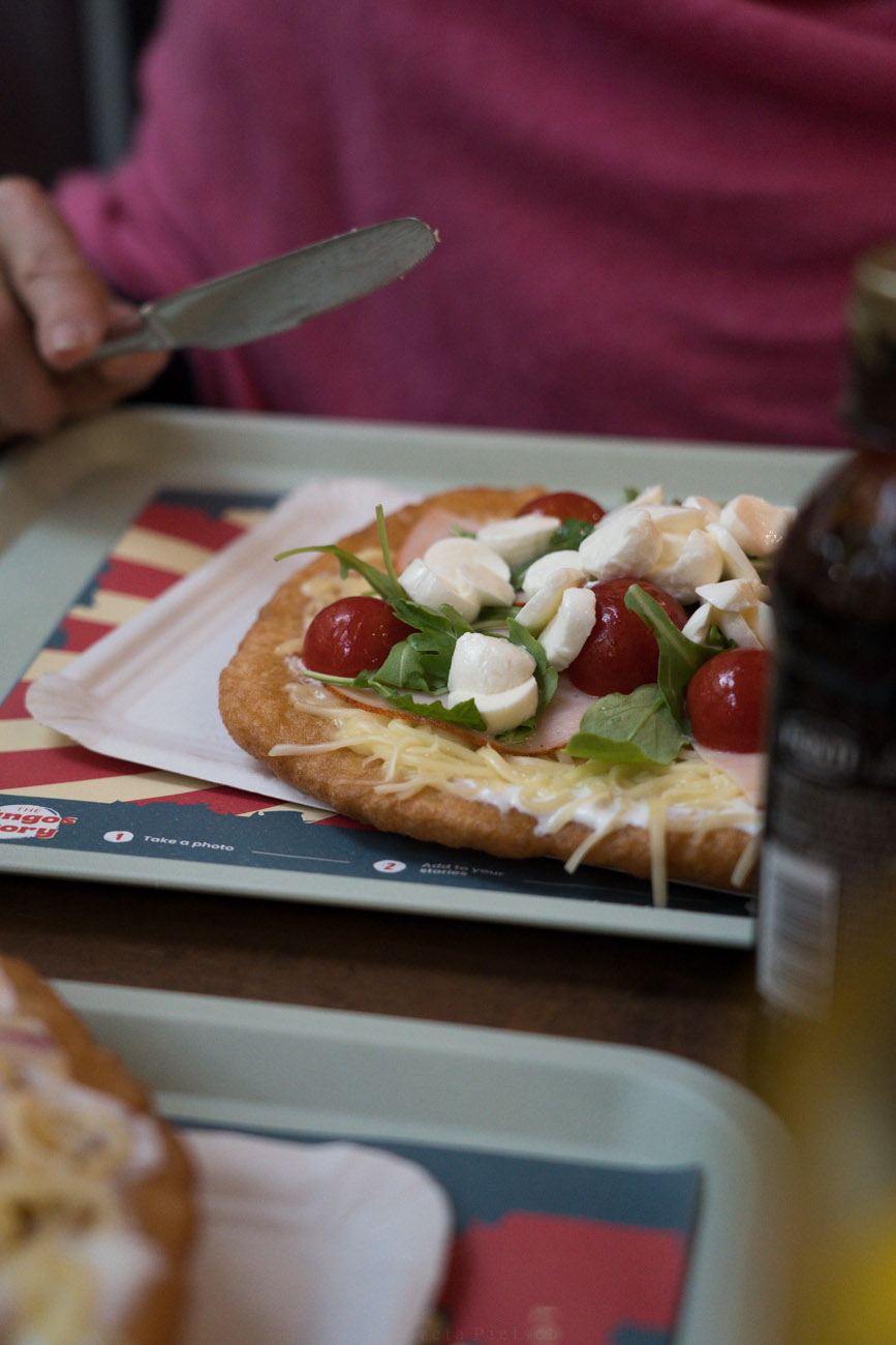 glutenfreie Langos auf einem Tablett mit Rucola, Tomaten, Mozzarella und Käse