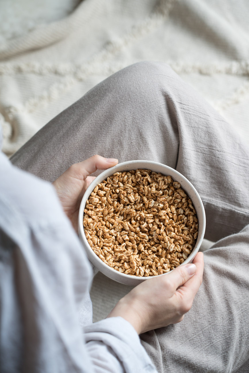 Glutenfreie Cerealien in einer Schale, steht auf einem Schoß und wirs von zwei Händen gehalten.