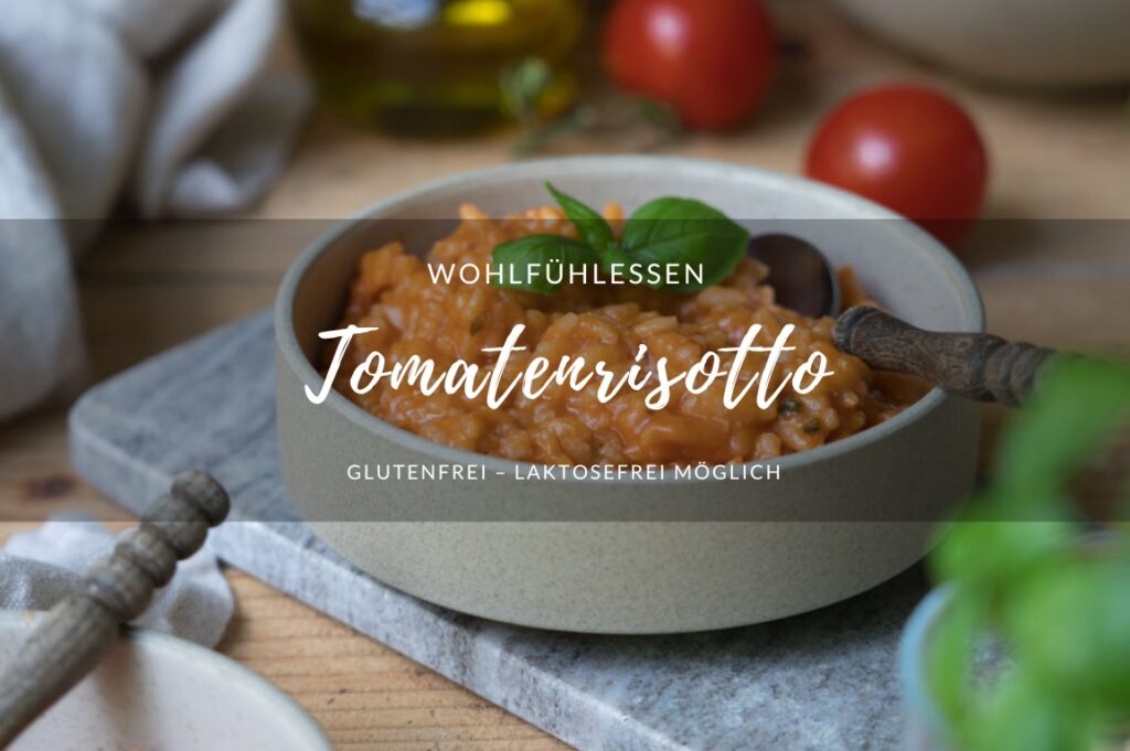 Titelbild für ein Rezept für Tomatenrisotto: Tomatenrisotto in einer beigen Schale auf einem Marmorbrettchen. ImHintergrund sieht man frische Tomaten und im Vordergrung etwas unscharf Basilikum.