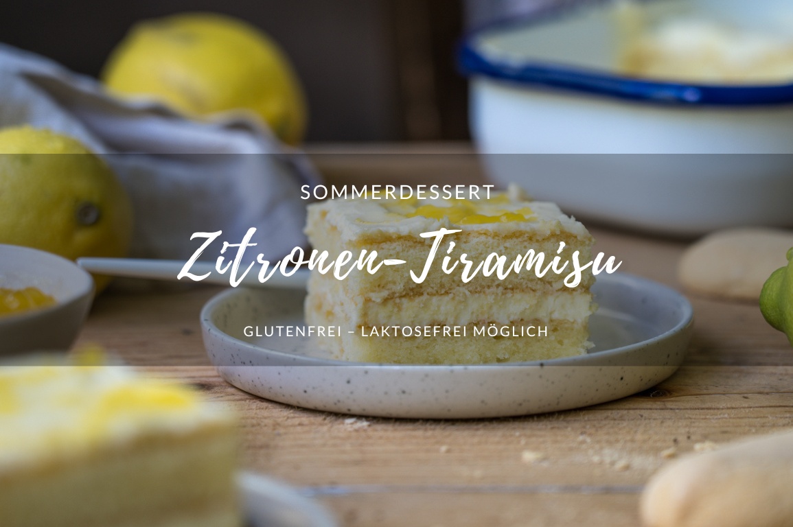 Ein Stück Zitronen-Tiramisu auf einem kleinen Teller, auf einem Holztisch Im Hintergrund sieht man eine Schale mit Tiramisu.