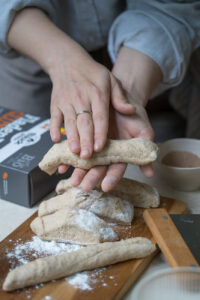 Eien PErson rollt den Teig für Stockbrot in den Händen zu einem Teigstrang.