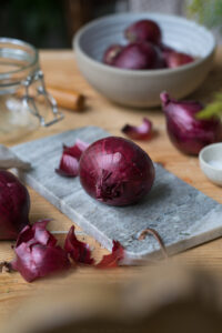 Eine rote Zwiebel auf einem Marmorbrettchen.