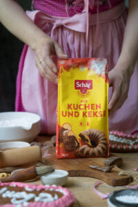Mic C für Kuchen & Kekse, eine Verpackung mit glutenfreiem Mehl steht auf einem Holzbrett, im Hintergrund sieht man Schalen, ein Nudelholz
