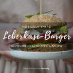 Zwei Hände halten einen Teller mit einem Leberkäse-Burger