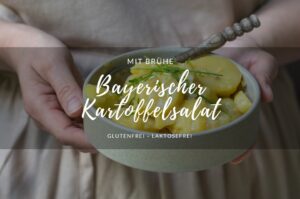 Ein Rezept für Bayerischen Kartoffelsalat. Eine Porzellanschale mit bayerischem Kartoffelsalat, gehalten von einer Person mit einer beigen Kochschürze.