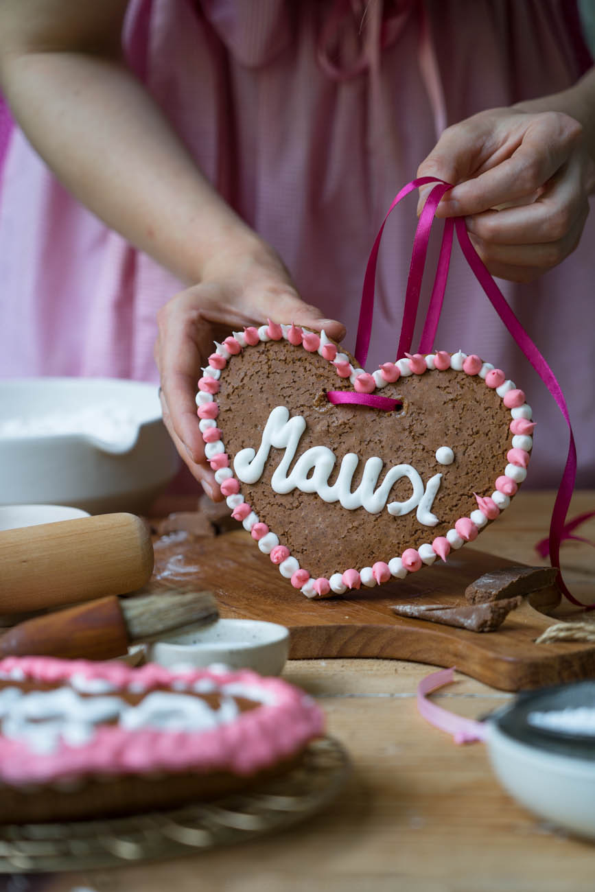 Ein Lebkuchenherz mit der Aufschrift "Mausi", gehalten von zwei Händen