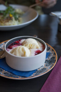 Ein tiefes Schälchen mit zwei Eiskugeln und heißen Himbeeren.