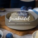 Eine Keramikschale mit einem Germknödel und Mohn-Zucker darauf. Im Vordergrund sieht man noch einen Knödel, Pflaumen in einer Schale.