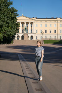 Eine Person steht vor dem königlichen Schloss in Oslo, Norwegen am frühen Morgen. die Person trägt eine Jeans und ein gestreiftes T-Shirt.