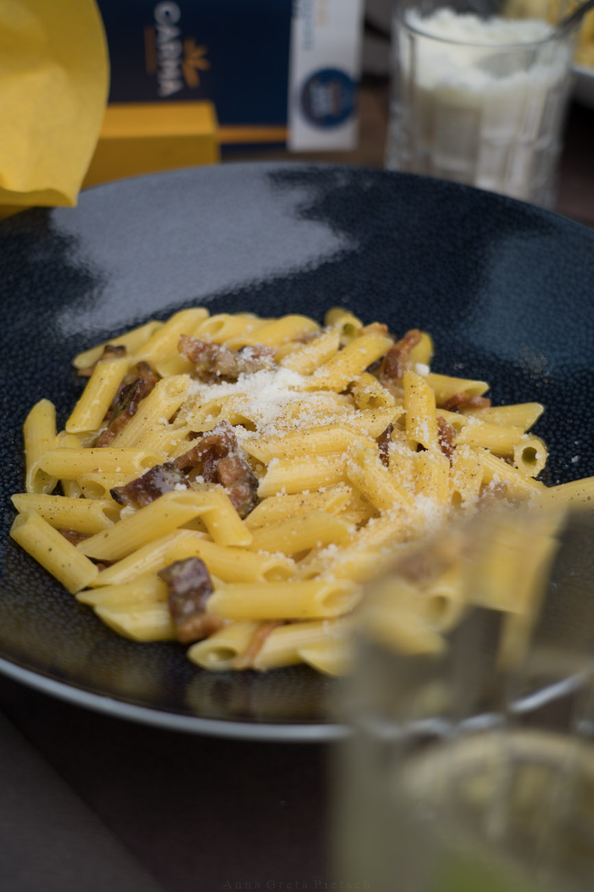 Ein schwarzer Teller mit glutenfreien Pasta und Carbonara-Soße.
