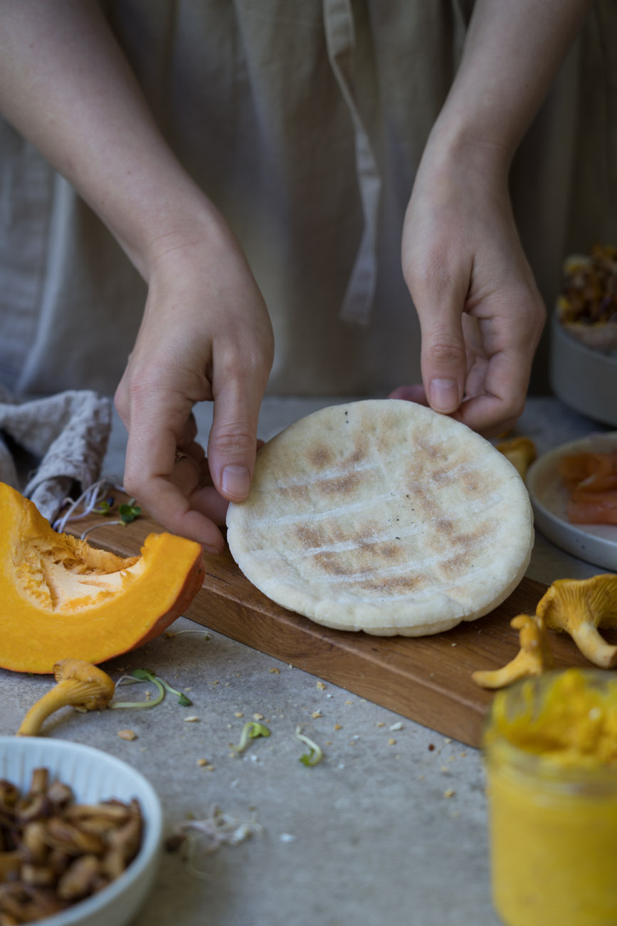 Eine glutenfreie Pita, gehalten von zwei Händen, auf einer Arbeitsfläche.