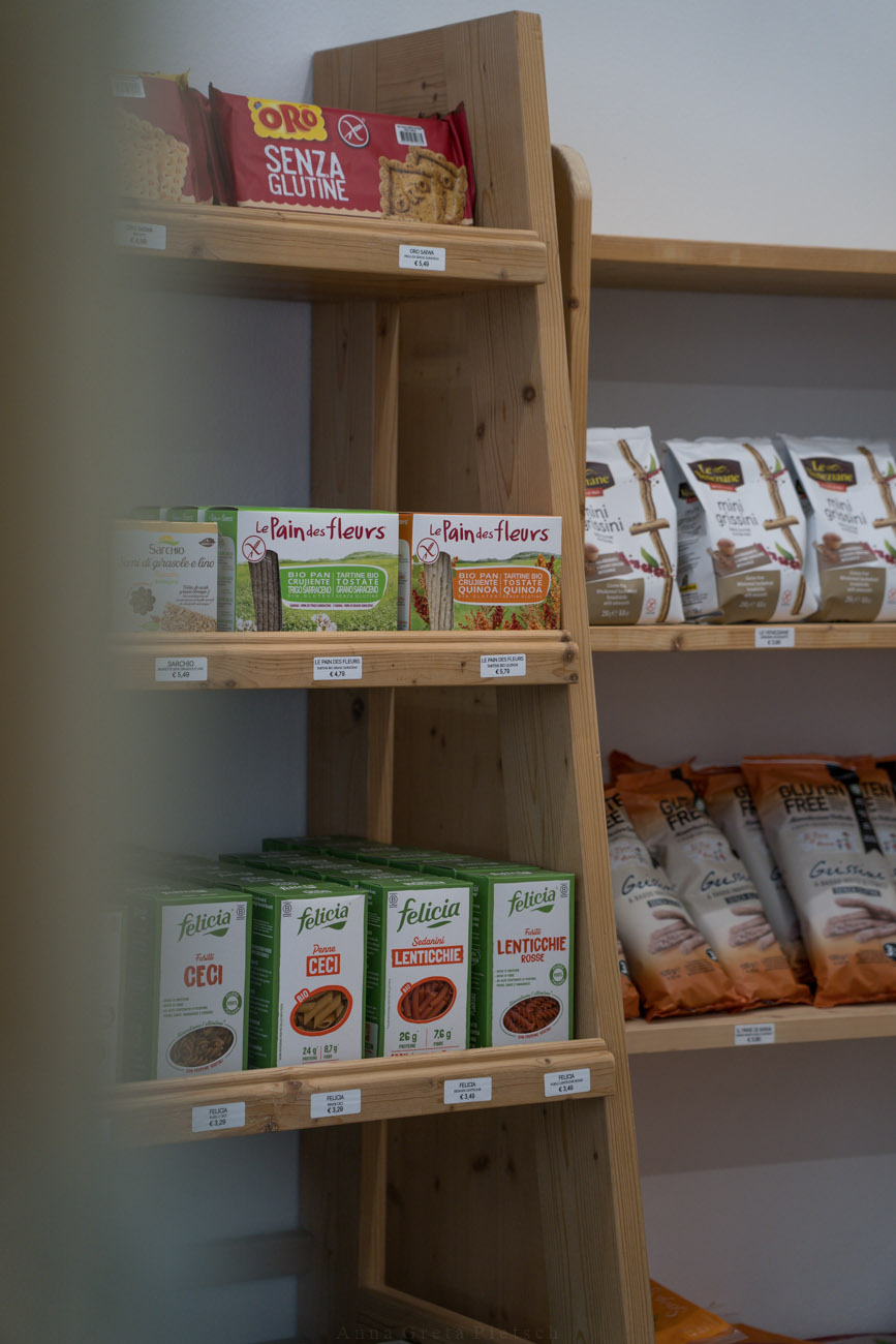 Glutenfreie Lebensmittel wie Brot, Nudeln und Kekse in einem Regal.