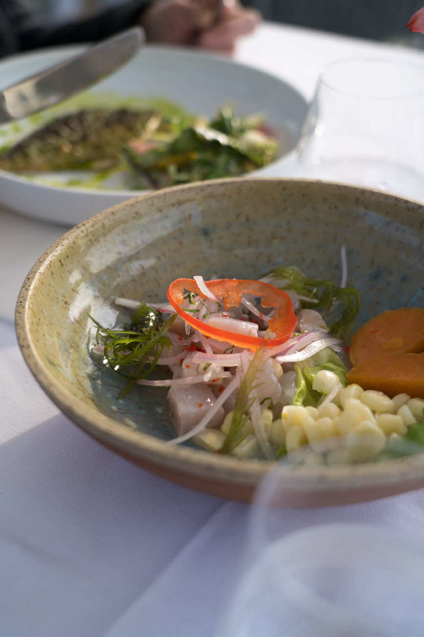 Ein weiß eingedeckter Tisch mit einem Teller voller Ceviche.