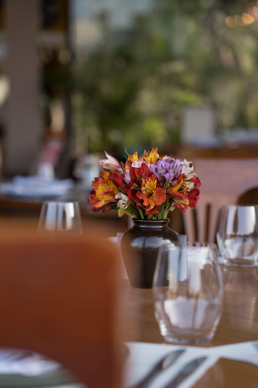 Ein gedeckter Tisch mit einem bunten Blumenstrauß in der Mitte.