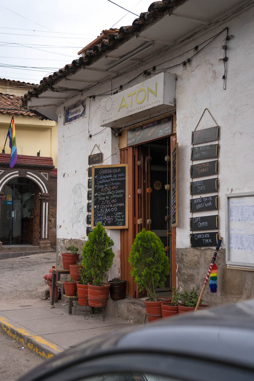 Die Außenansicht eines Restaurants in Cusco. Es stehen einige terrakottafarbene Blumentöpfe davor und es hängen Kreidetafeln an der Wand.