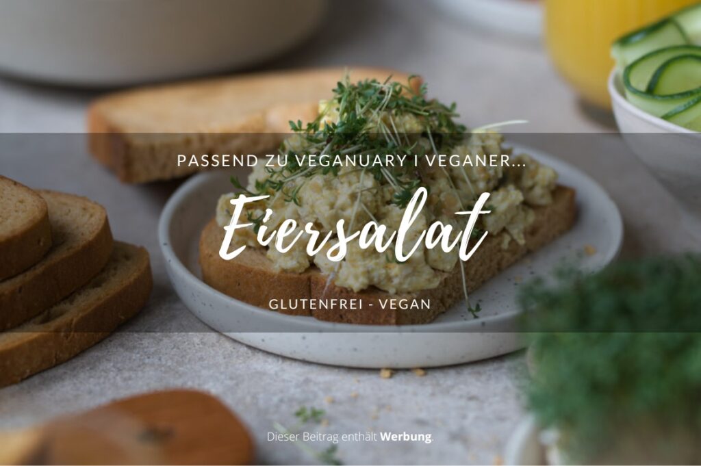 Ein gedeckter Frühstückstisch. In der Mitte steht ein kleiner Teller mit einer Brotscheibe, die mit selbstgemachtem veganem Eiersalat belegt ist.