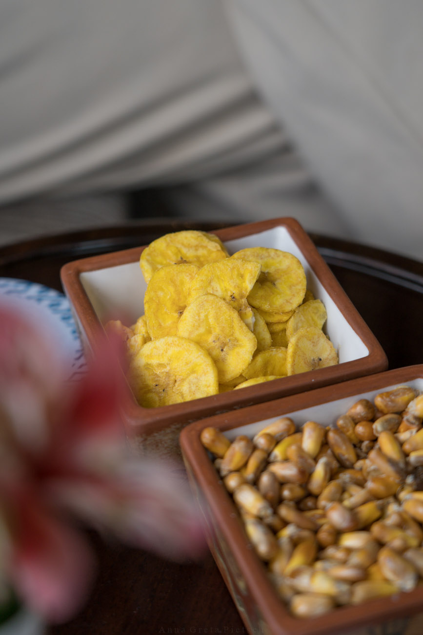 Zwei Schälchen mit Snacks. Frittierte Bananenscheiben sind in einer Schale und in der anderen geröstete Maiskörner.