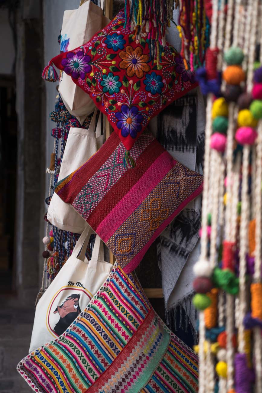 Man sieht den Eingang zu einem Souvenirladen in Cusco, Peru. Es hängen drei Kissenhüllen übereinander.