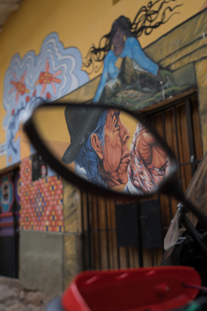 Ein Murial spiegelt sich in einem Motorrad-Spiegel und zeigt eine indigene Frau.