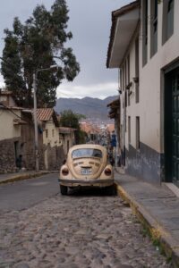 VW-Käfer in Cusco, Peru auf einer Straße mit Kopfsteinpflaster.