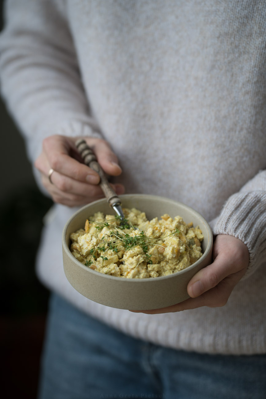 Eine PErson hält eine Keramitschüssel in beiden Händen. Darin ist veganer Eiersalat.