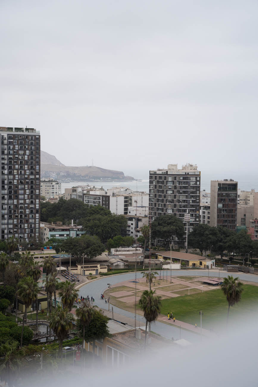 Hochhäuser in Lima, Peru. Man sieht einen Sportplatz und das Meer im Hintergrund.