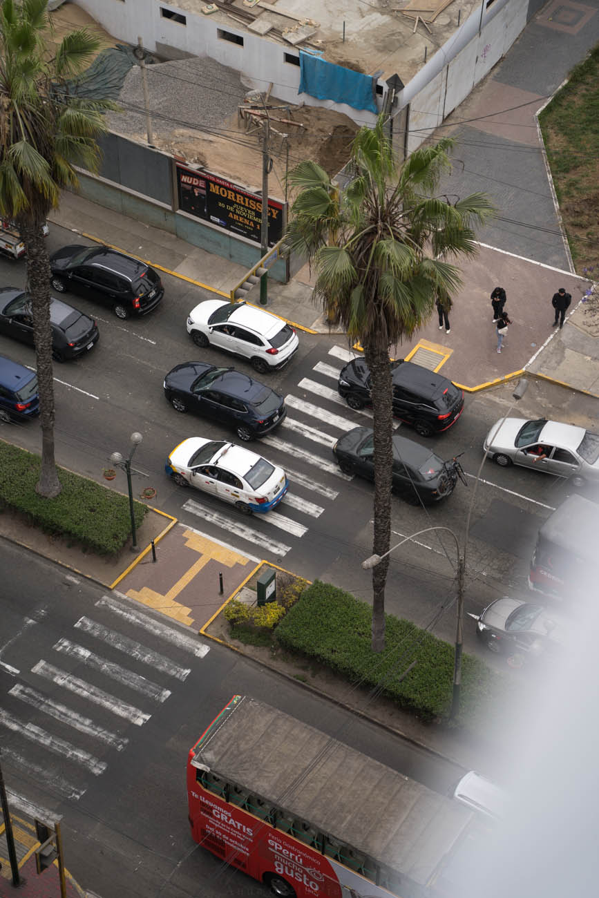 Ein breiter Zebrastreifen auf einer sechsspurigen Straße in Lima, von oben aus einem Hochhaus fotografiert.