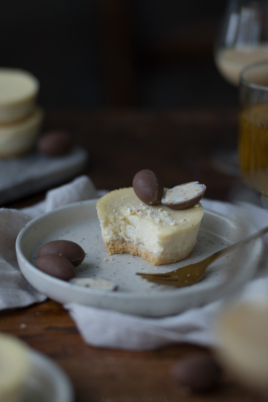 Ein Min-Cheesecake auf eienm kleinen Tellerchen suf einer Kuchentafel. Es ist mit Schoko-Ostereiern dekoriert.