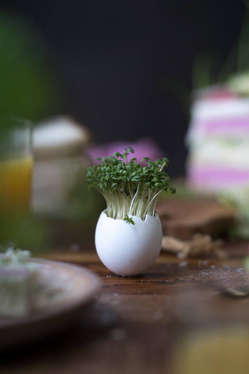 Osterdekoration auf einem gedeckten Tisch. Ein Hühnerei, aus dem frische Kresse wächst.