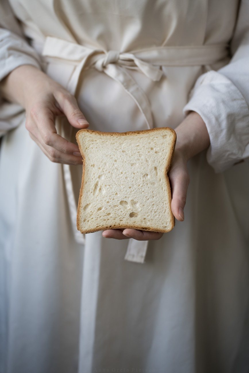 Eine Person mit einer beigen Schürze hält eine Toastscheibe in der Hand.