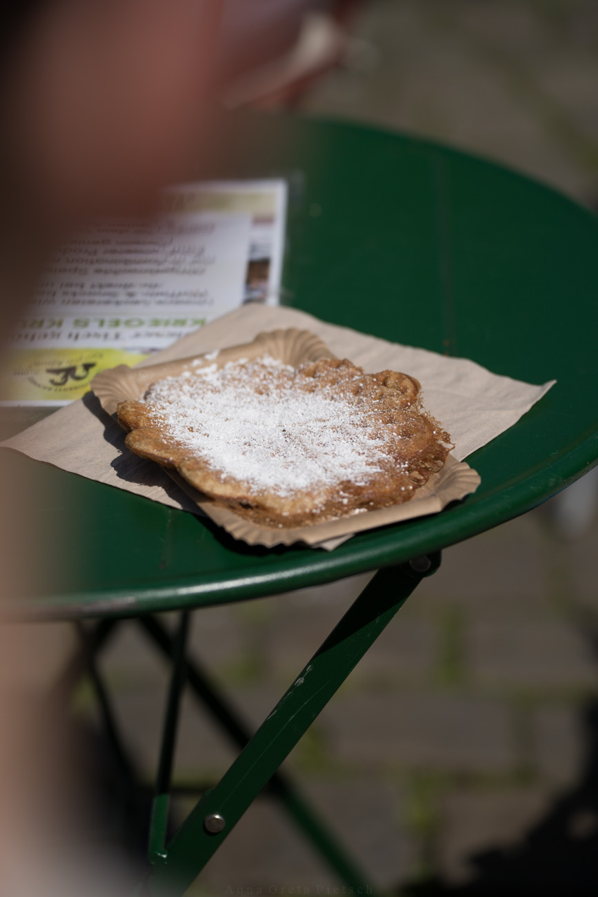 Ein grüber Metalltisch mit einem Pappteller. Darauf liegt eine frisch gebackene Waffel.