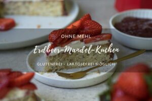 Ein Stück Erdbeerkuchen auf einem kleinen Teller steht in der Mitte einer Kaffeetafel. Man sieht im Hintergrund und Vordergrund noch weitere Kuchenstücke, den Kuchen auf einer Kuchenplatte, Erdbeeren und einen roten Espressokocher.
