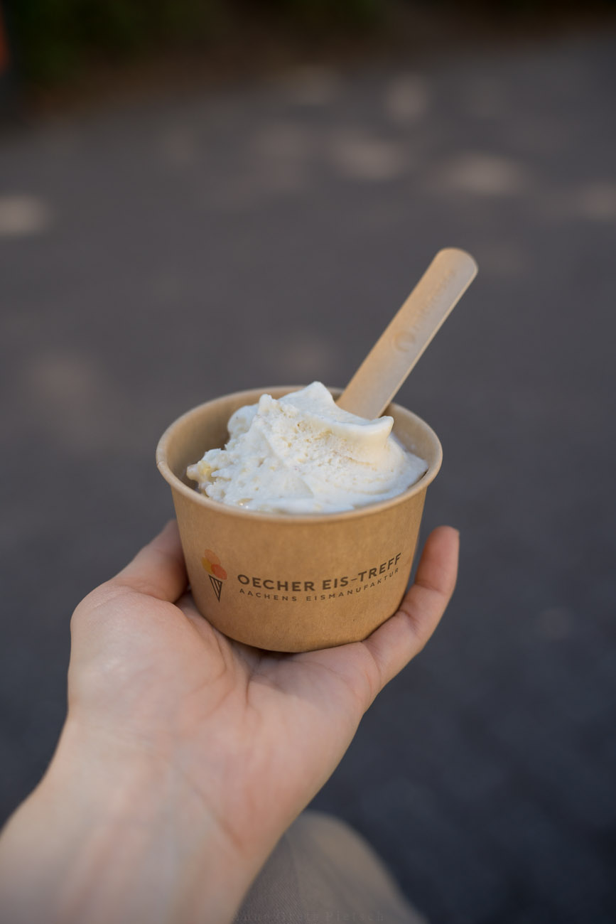Eine Person hält einen Eisbecher mit einer Kugel Eis in der Hand. 