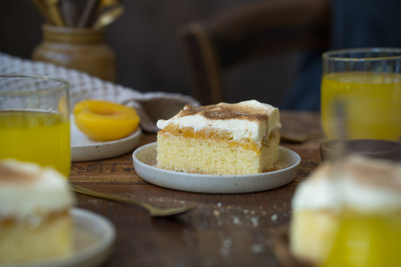 Eine Kaffeetafel mit quadratischen Stücken Fantakuchen, verteilt auf kleine Teller.