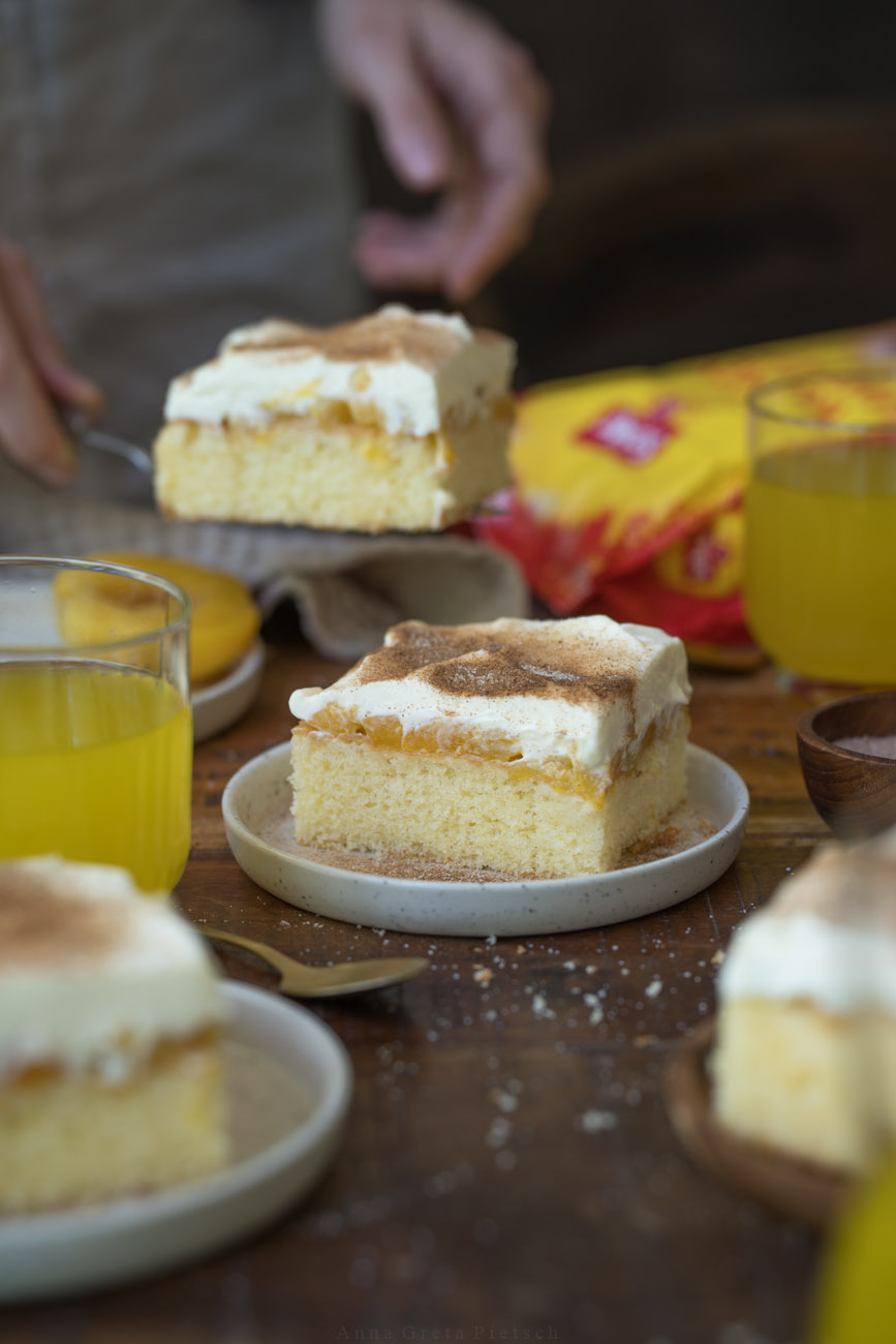 Eine Kaffeetafel mit quadratischen Stücken Fantakuchen, verteilt auf kleine Teller.