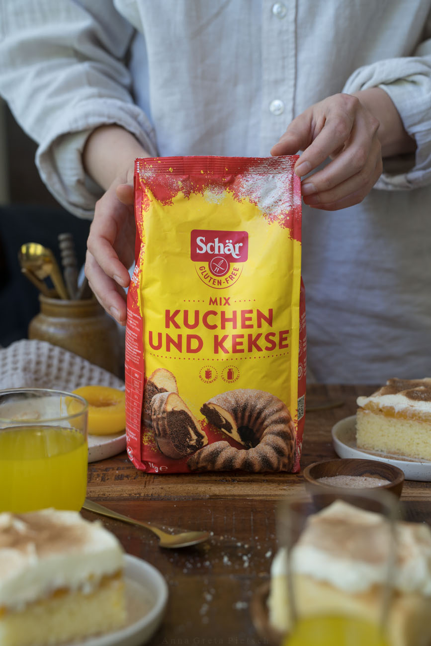 Eine Arbeitsfläche, in der Mitte wird ein Paket mit glutenfreiem Mehl von zwei Händen gehalten.